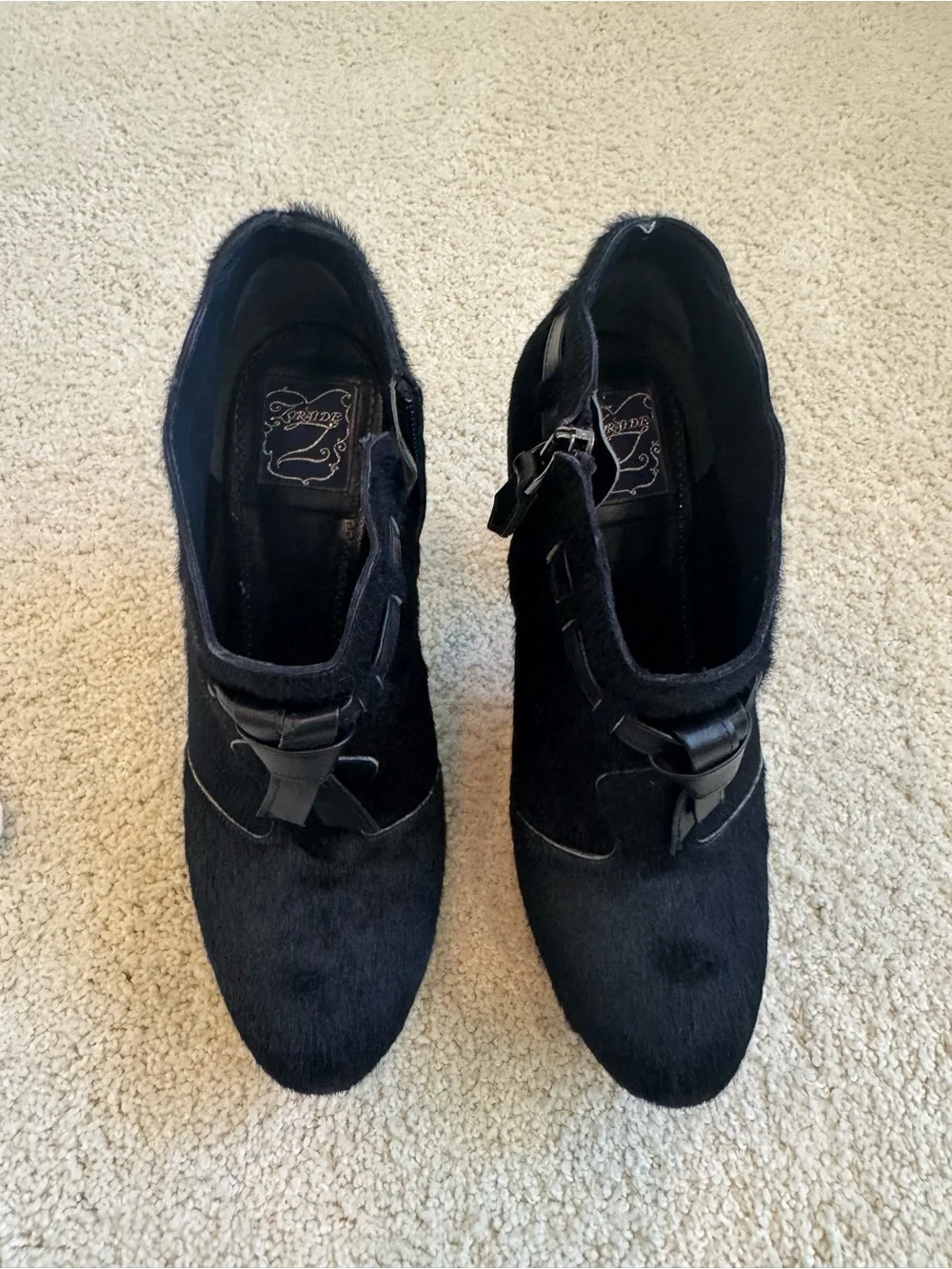 ZORAIDE black calf hair ankle booties with leather strap and tassel accents.